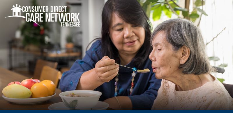 Caregiver feeding an elderly woman